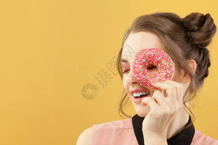 快乐的女士拿着甜圈在多彩黄色背景图片