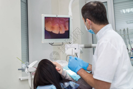 牙科医生用相机检查病人的牙齿图片