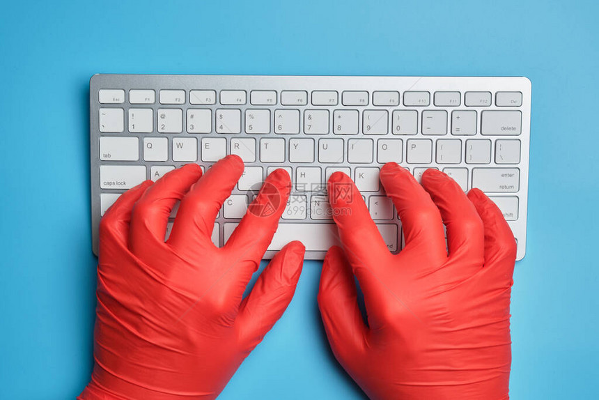 红手套医生在蓝背景的键盘上打图片