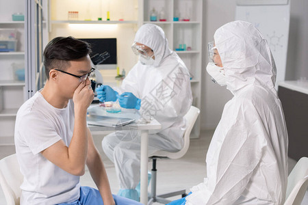 生物危害西装和呼吸口罩专家与孤立研究室的冠状人交谈图片