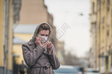 身戴保护面具的年轻妇女在街上用图片