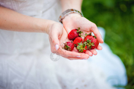 一个漂亮的年轻女孩手里拿着草莓图片