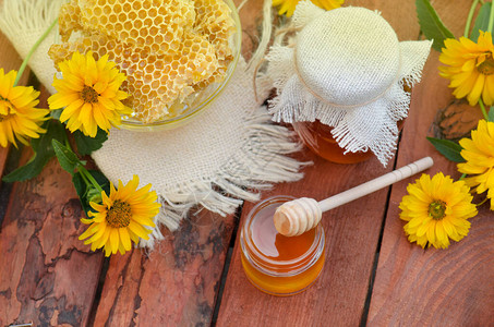 蜂蜜的罐子有鲜花背景的木桌上的蜜蜂窝背景