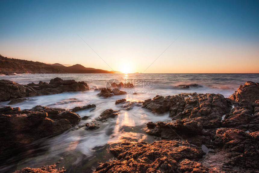 太阳落山时波浪冲上科尔西卡岩石海岸线的长线图像图片