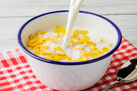 早餐配玉米片将牛奶倒入装有玉米片的碗中酸奶溅出成玉米片健康的早餐图片