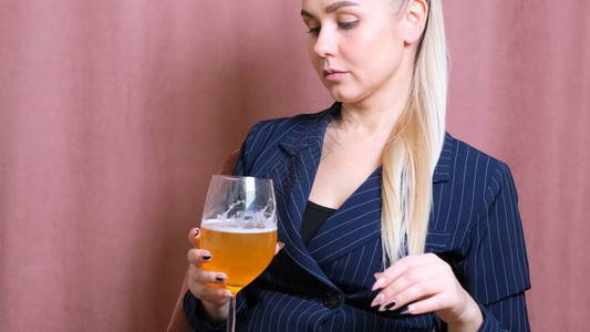 年轻的金发女郎手持起泡酒啤酒的女酗酒女人下班后在图片