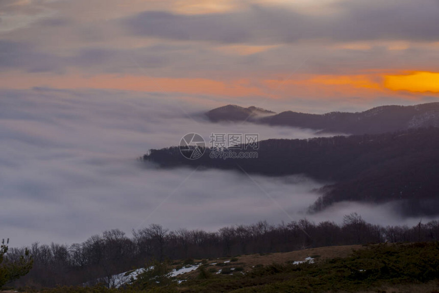 日出时的雾山在长时间曝光下拍摄图片