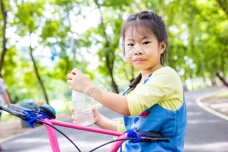 可爱的小女孩在公共城市公园享受骑自行图片
