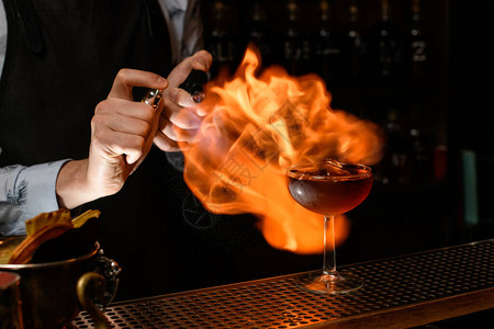 酒保专业喷洒和在葡萄酒杯中烧冷褐色酒精饮料图片