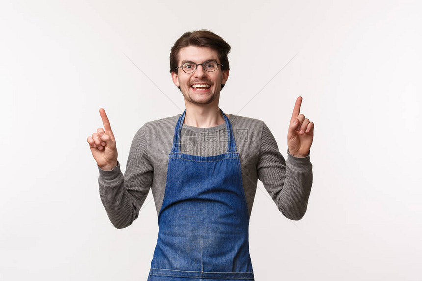 在咖啡店兼职工作梦想开办自己的企业学习如何煮咖啡穿围裙手指向上和对着镜头微笑的快乐逗帅气的留着图片