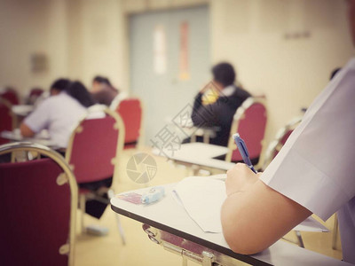 大学本科生的软焦点在纸上答题纸上拿着铅笔写字坐在红色演讲椅上参加考试室或教室的期末考图片