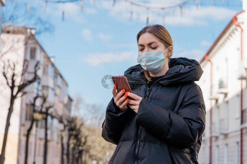 在城市使用智能手机戴防护医用口罩的女肖像健康与安全N1H1冠状防护图片