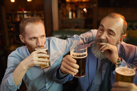 两个人手握着眼镜坐在酒吧里喝着啤酒享图片