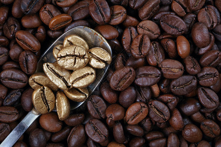 一堆咖啡豆上的金咖啡豆奢华和独创概念勺子里的金色咖啡豆咖图片