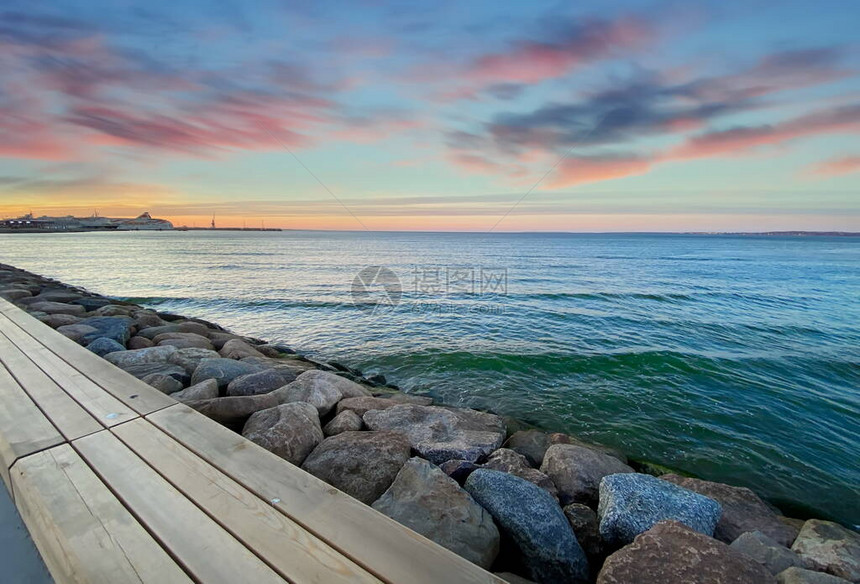 海日落五颜六色的天空天际线海水的光反射海滨长廊和海滩上的石头蓝天和塔林地平线港口的粉图片