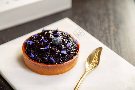 蓝莓派放在大理石盘上金勺子在餐厅里图片