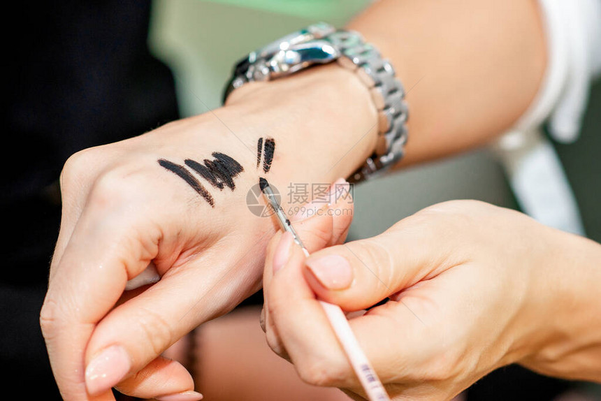 化妆师用她手上的刷子近距离测试黑色化妆品图片