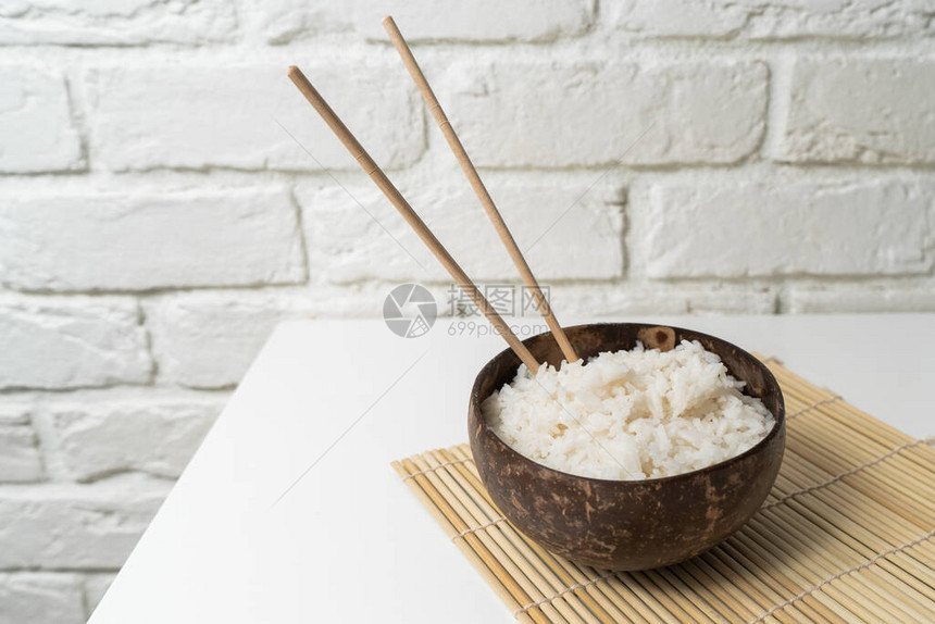 白米在白色背景的椰子碗中的白饭带大米和竹筷图片