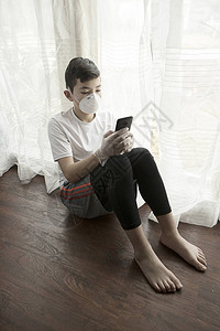 一张戴着口罩手套和手机的男孩的概念照片图片
