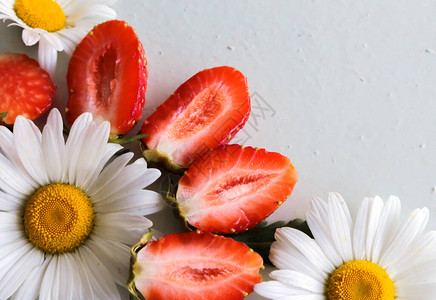 浅色背景上的雏菊和红草莓背景图片