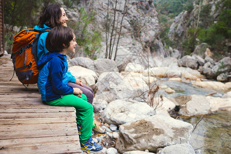 一个背着包的女人和一个孩子坐在山河的岸边图片