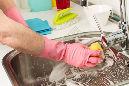 男人用海绵和清洁剂清洁不锈钢水槽图片