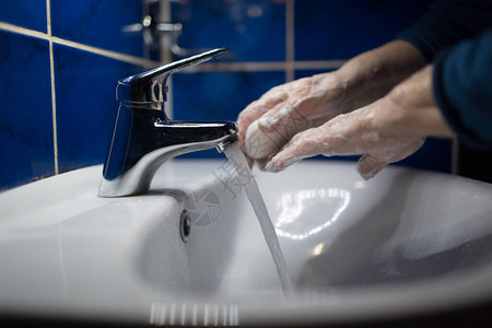 在水龙头下妇女用肥皂洗手图片
