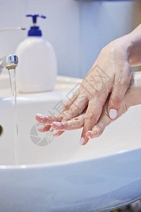 近距离观察妇女使用肥皂和洗手在卫生间水龙头下洗手的情况图片