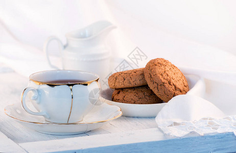 白瓷茶杯牛奶壶和新鲜的燕麦饼干英国早餐还有饮料美食和白桌布图片