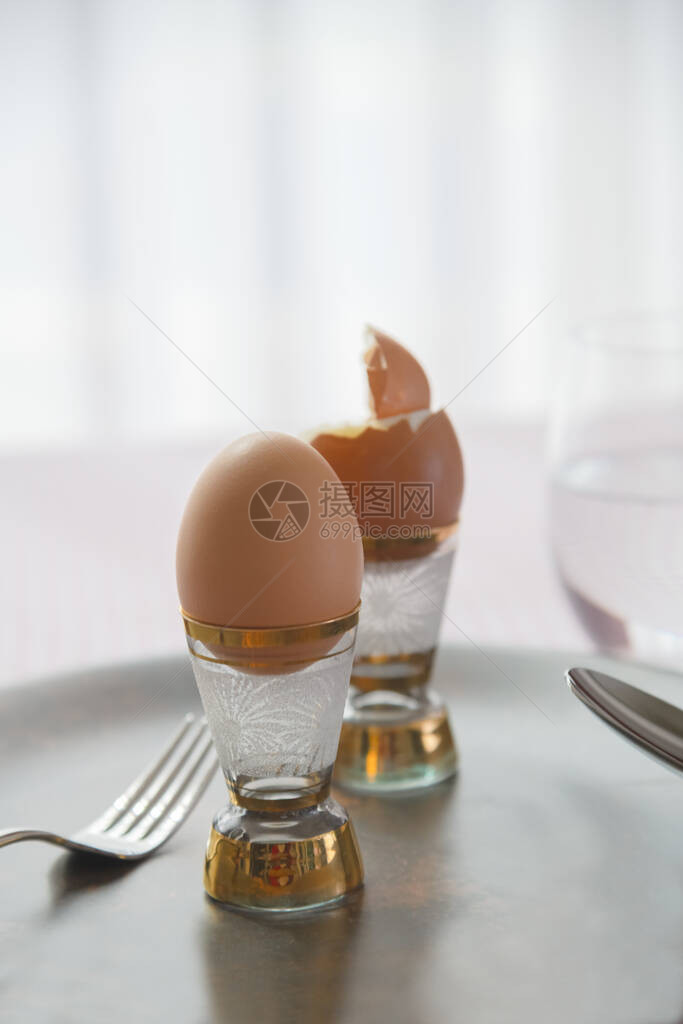 陶瓷黑盘上两个煮鸡蛋放在一张桌布背景的餐桌布图片