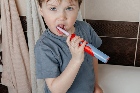 婴儿在洗脸盆前用电动刷牙直视镜头图片