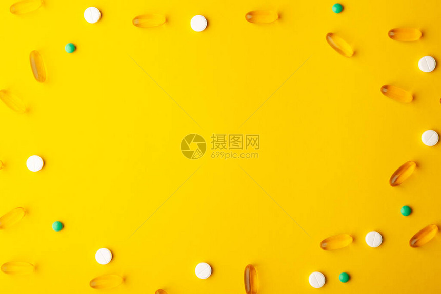 许多分散的药物维生素药丸鱼油软胶囊药片在治疗期间放置在黄色表面膳食补充剂中心复制图片