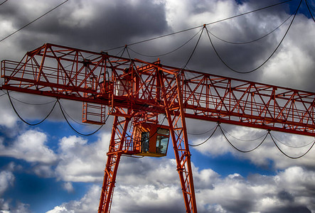 天脊龙门龙门起重机的工作工业用地货物装载反对多云的天空背景