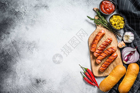制作自制热狗的原料香肠新鲜出炉的面包芥末番茄酱黄瓜白色背景顶视图片