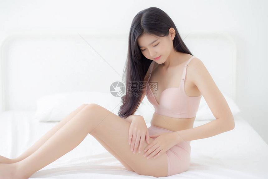 美丽的亚洲年轻女用乳霜和乳液抚摸皮肤腿部光滑图片