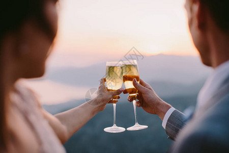 蜜月情侣在日落时一起喝香槟在山上风景的外图片