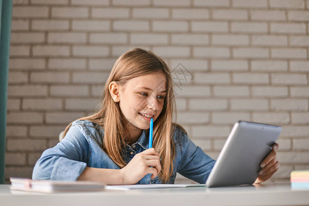可爱的少女学生在家里用平板电脑做作业孩子使用小工具进行学习隔离期间的教育远程学背景图片
