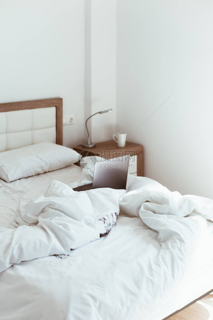 工作家庭隔离自我隔离锁定概念在未整理的床上的笔记本电脑舒适的远程家庭办公室拥有阳光和简约设计的现代公寓在大流图片