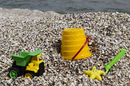 儿童玩具桶子铲子铁铲汽车贝壳海滩上的图片