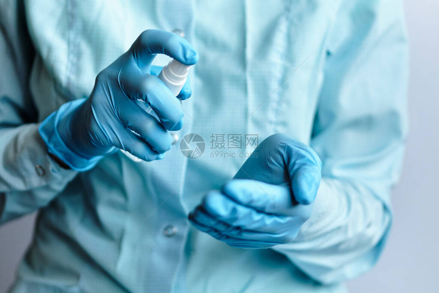 一名蓝色医疗手套医生手持防疫消毒剂和喷雾剂图片