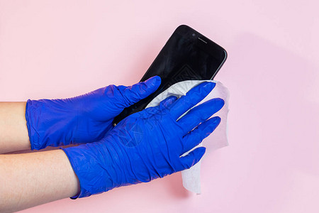 戴着乳胶手套的手用防腐剂对智能手机进行消毒预防头孢的概念大流行期图片