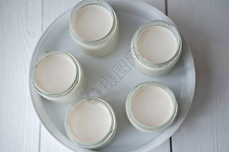 在酸奶机的玻璃罐中自制有机酸奶自动酸奶机在家制作发酵乳制品检疫概念期间的酸奶背景图片