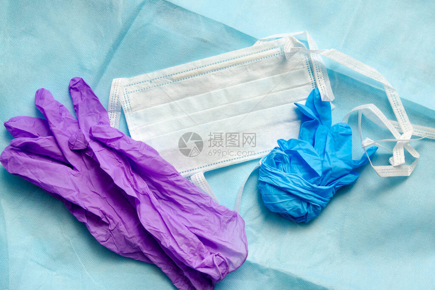 蓝色无纺布材料上的一次医用口罩和乳胶手套图片