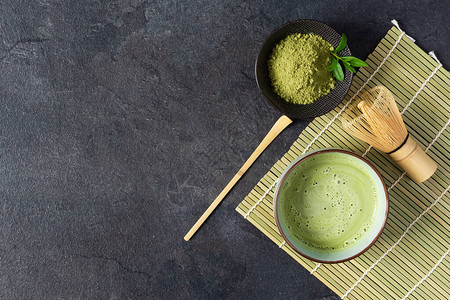 黑色背景顶视图上的绿色抹茶饮料和茶配件日本茶道概念用于冲泡抹茶的图片