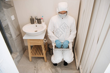 在浴室使用膝上型的男子穿着哈兹马特西装医疗面具乳胶背景图片