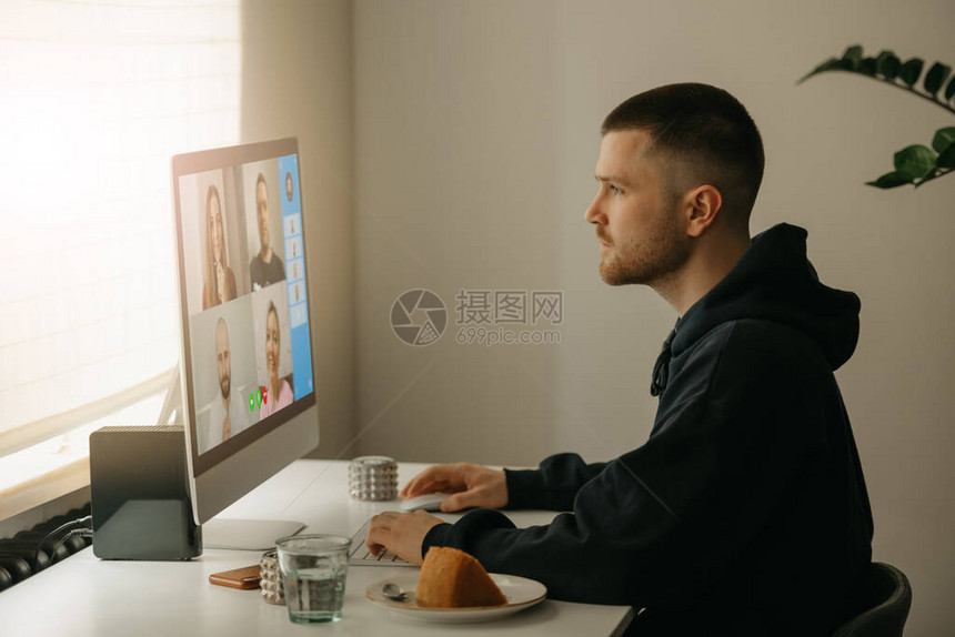 远程工作一名男子在与台式电脑上的同事进行视频通话一个在家中紧张工作的图片