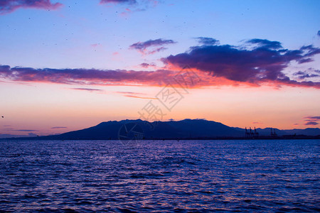 在海面的黄昏时期自然山上日落美丽的乌云以橙色漆成自然背图片