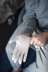 灰色衣服的男子戴上医用乳胶手套图片