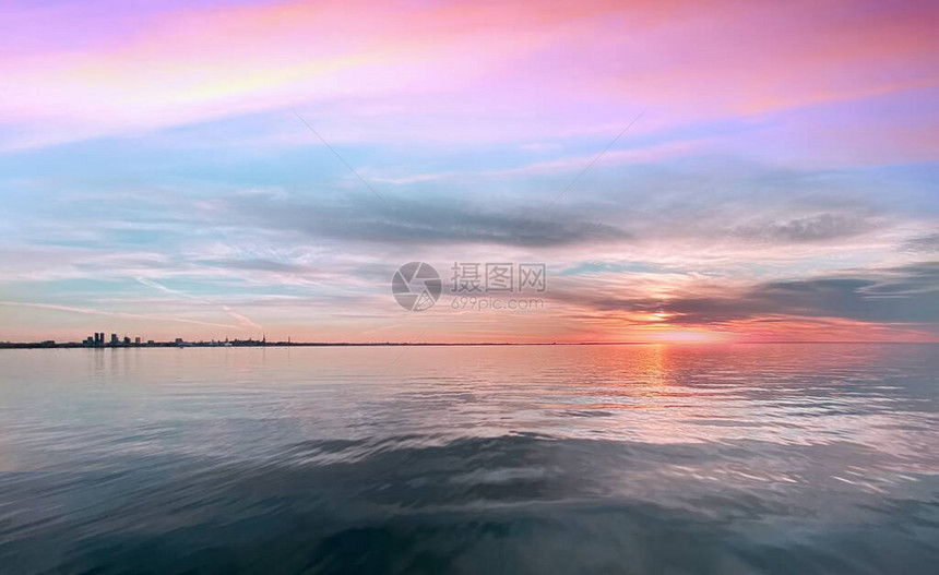 海上日落粉色蓝金黄色五颜六色的太阳光反射在海水波贝壳云彩上美丽的天空图片