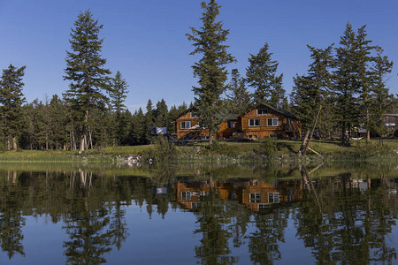 在一片平静的蓝水湖中海岸线和一栋木屋被反射图片
